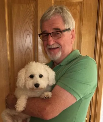 Jim at home, holding his small white dog.